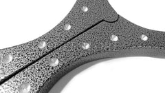 Close-up of The Cuffstore Heavy Aluminum Cangue with Padlock Bondage Yoke Shrews Fiddle Restraint, a black speckled, Y-shaped device with metallic rivets and visible seam, shown against a white background.