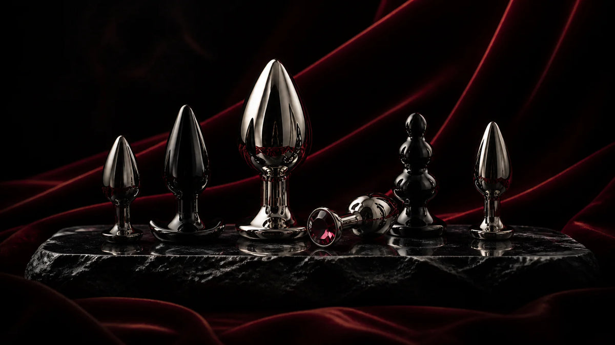 A lineup of polished stainless and black plug forms on an obsidian pedestal.