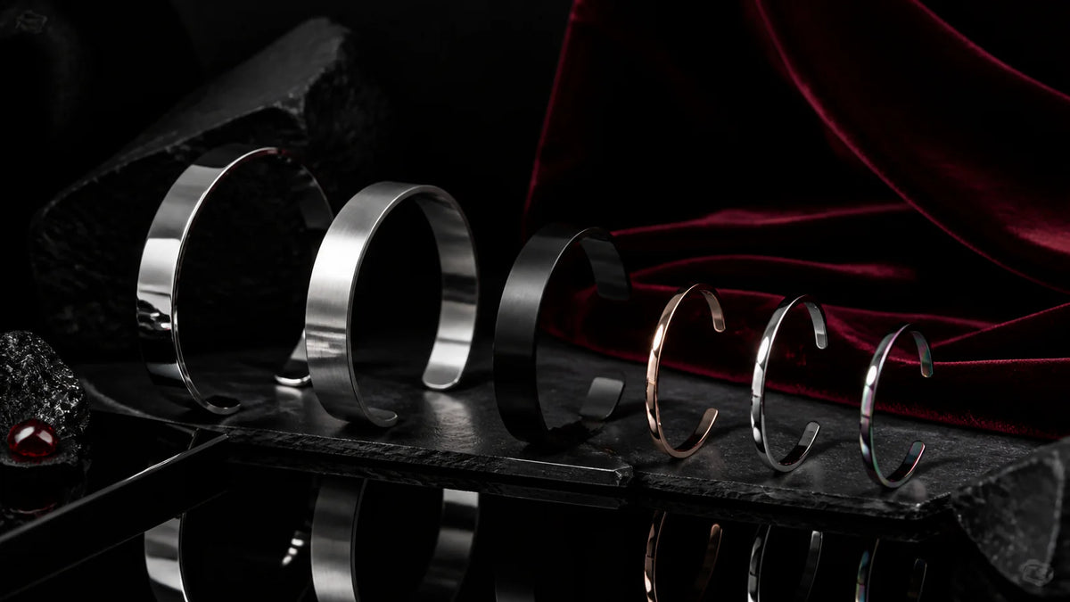 Elliptical stainless cuffs and bracelets in polished, satin, black, and rose-gold finishes.
