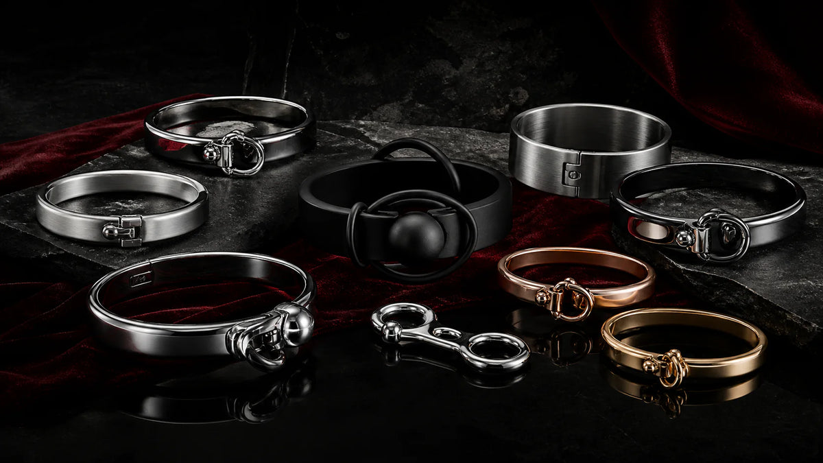 Polished, satin, black, and rose-gold locking bracelets arranged on velvet.