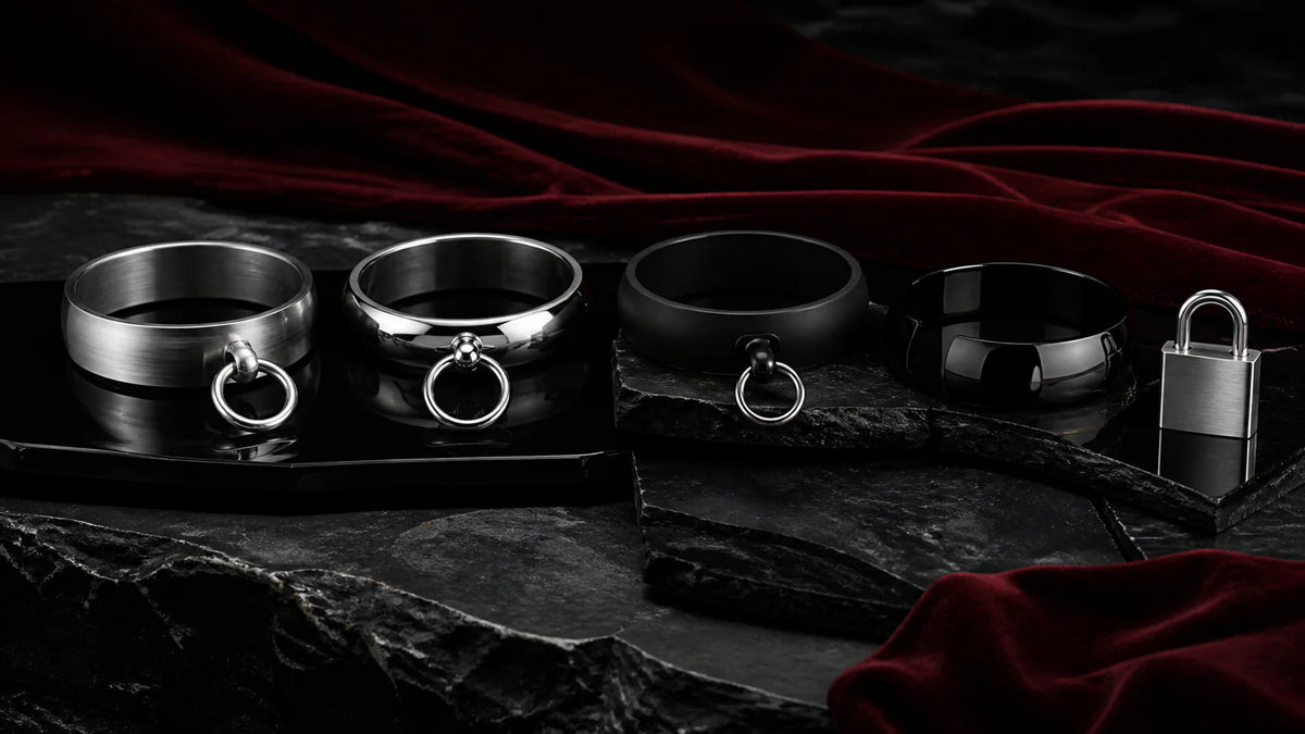 Satin, polished, and black collar arcs with rings and a padlock on stone.