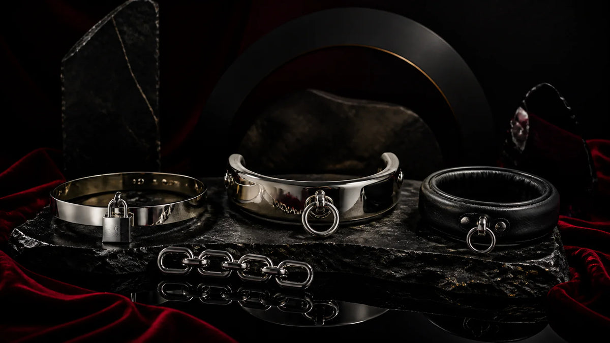 Curved stainless and leather O-ring collars with a short connector chain on stone.