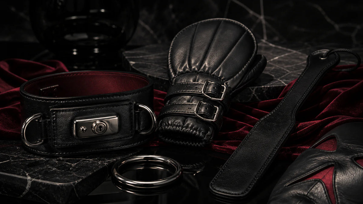 Black leather collar, fist mitt, and slapper with silver hardware on oxblood velvet.