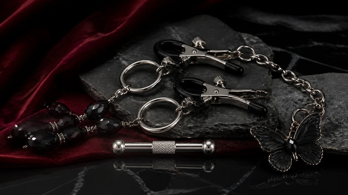 Polished clamps, black beaded details, and a short chain arranged on dark stone.