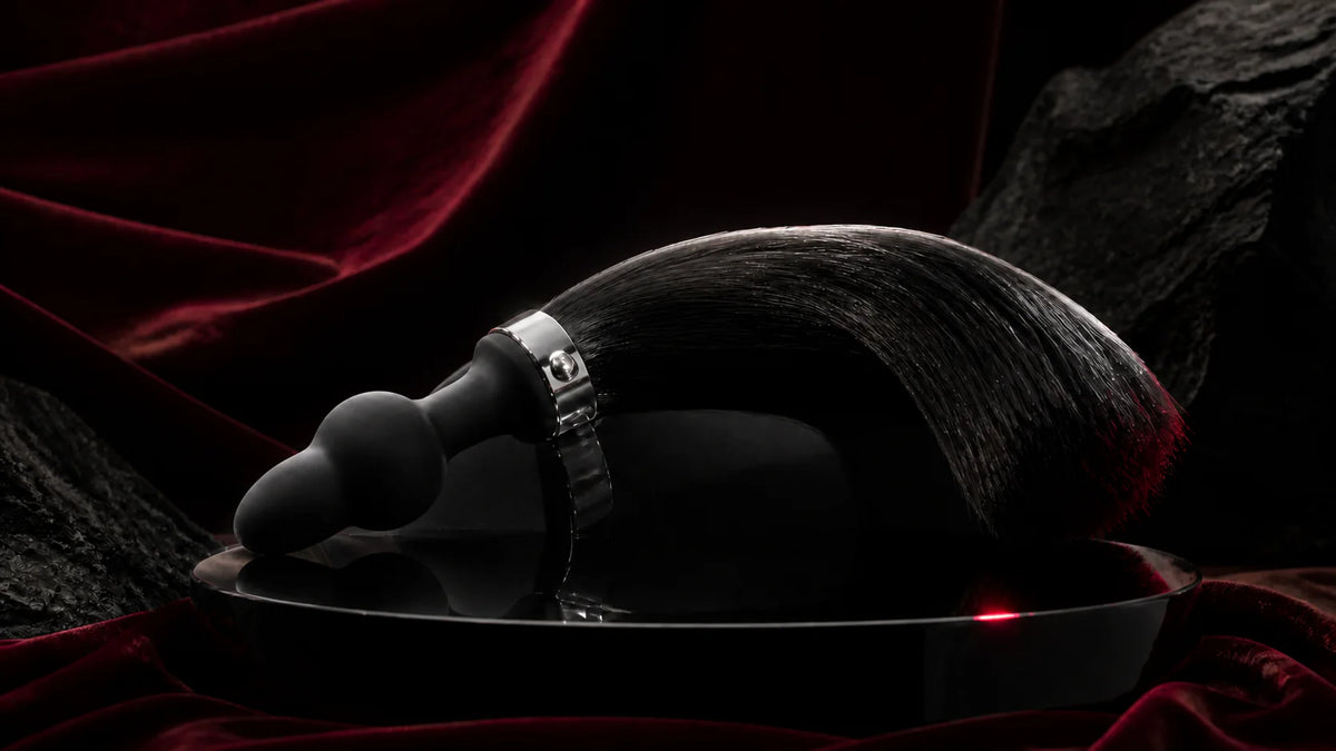 A black horse-tail sculptural form with a rounded base on dark stone.