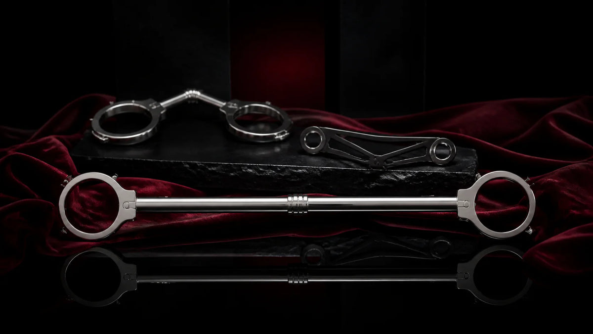 A polished rigid spreader bar with cuff details on an obsidian pedestal.