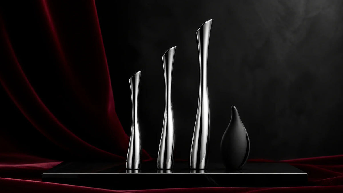 Slender polished stainless and black silicone sound forms on an obsidian slab.